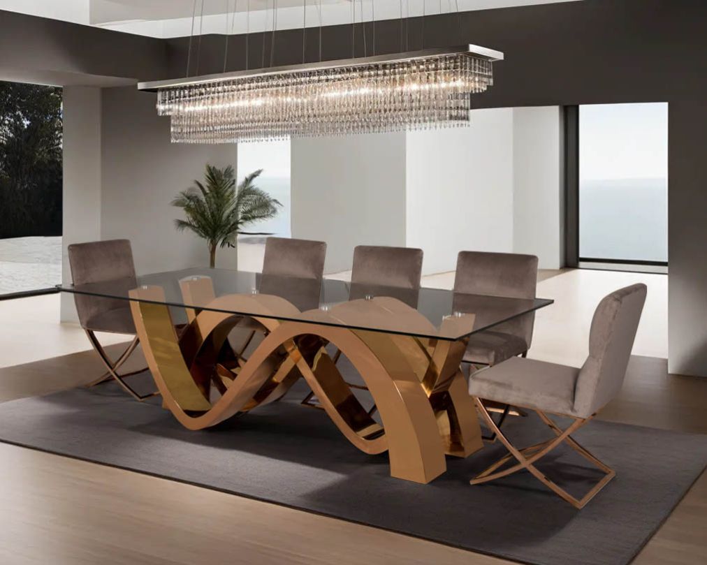 This 8-seater dining table with clear tempered glass top comes with an artful abstract wave-shaped concave design finished in a shiny rose gold plated stainless steel base in rose gold finish Dining chair upholstered in fabric with rose gold plated stainl